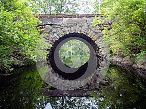 Stone Arch Bridge in Bristol, Maine, over the Pemaquid River from canoe on a calm summer morning