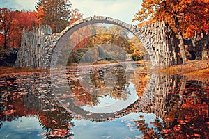 Stone arch bridge Kromlau made of basalt stones, in brightly colored autumn, called v or devils bridge