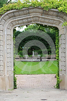 A stone arch entry, covered in a vine, framing a sunken garden, at Rotary Botanic Gardens in Janesville, Wisconsin