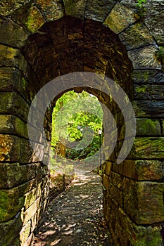 Stone arch tunnel in detail going into woods on trail in Central Park New York City