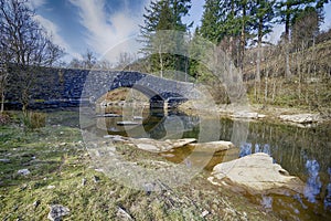 A stone arched bridge ofer the rocky stream in Wales UK