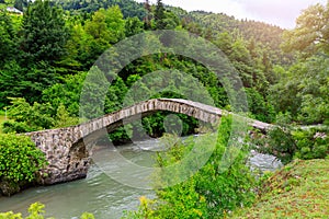 The stone arched bridge over the mountain river in Georgia