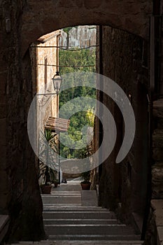 Stone archway leading to a curved staircase in Pitigliano, Italy