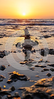 Stone balance on the beach at sunset. Pyramid of the small pebbles on the beach