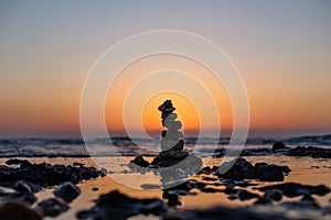 Stone balance on the beach at sunset. Pyramid of the small pebbles on the beach