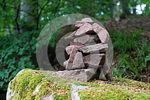 stone balance on big rock covered by the moss in a forest