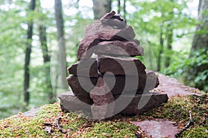 stone balance on big rock covered by the moss in a forest