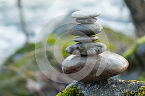 Stone balance on rock covered by moss in border river