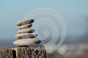 Stone balance on wooden fenceon blurred rural landscape background