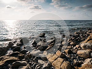 Stone beach at sea shore, close up. Ocean water waves at sunset, relaxation and tranquil nature background