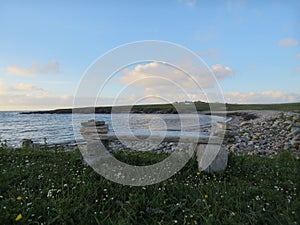 A stone bench on a beach overlooks a bay at sea