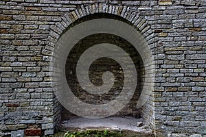 Stone brick antique arch is a window. Northern Europe, the castle. Fortress wall made of gray bricks.