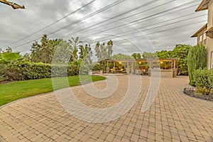 Stone brick driveway and patio with fire pit and dining area under a pavilion