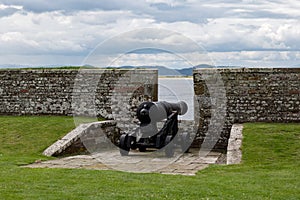 Stone brick protective wall and war cannon at barracks complex in historical Fort George, Scotland