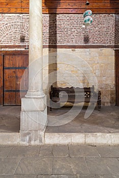 Stone bricks wall and aged wooden couch at main hall of historic Mamluk era Beshtak Palace, Cairo photo