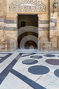 Stone bricks wall and opened door leading to passage at the courtyard of Sultan Barquq Mosque, Cairo