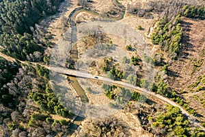 Stone bridge across small river in the forest. sunny spring landscape. aerial top view