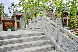 Stone bridge with bass-relief before Chinese traditional buildings on sunny day