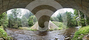 Stone bridge crosses a stream in Eagle mountains Orlicke hory during summer time.