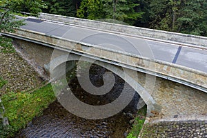 Stone bridge crosses a stream in Eagle mountains Orlicke hory during summer time.