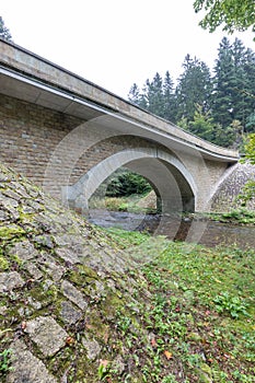 Stone bridge crosses a stream in Eagle mountains Orlicke hory during summer time.