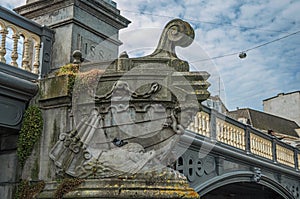 Stone bridge over canal decorated by sculpture of ship`s bow and sunny blue sky in Amsterdam.