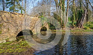 Stone bridge over the River Leach in the Cotswold village of Southrop, Gloucestershire, UK