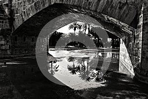 Stone bridge and reflections in a park puddle