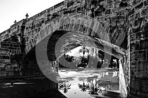 Stone bridge and reflections in a park puddle