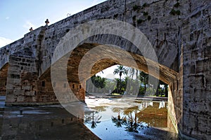 Stone bridge and reflections in a park puddle