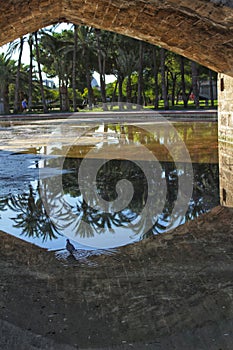 Stone bridge and reflections in a park puddle