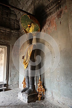 Stone buddha religous site in cambodia yellow, gold scarf and umbrella, angkor wat, hindu religon