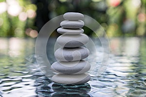 Stone cairn on green blurry background, light pebbles and stones