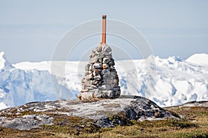 Stone cairn and marker with the Ilulissat icefjord in the background in Ilulissat, Greenland