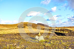 Stone cairn in an open valley with yellowish dry grass, mountains against blue sky