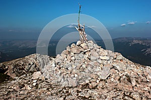 Stone cairn with sticking poles. Pile of rocks on the top of mountain