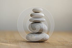 Stone cairn on striped grey white background, five stones tower, simple poise stones, simplicity harmony and balance