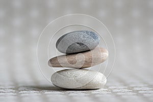 Stone cairn on striped grey white background, three stones tower, simple poise stones, simplicity harmony and balance