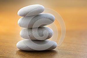Stone cairn tower, poise stones, rock zen sculpture, light white pebbles on wooden background