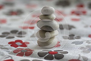 Stone cairn on white background with flowers stars, five stones tower, simple poise stones, simplicity harmony and zen balance