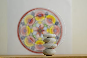 Stone cairn on white and colorfull red yellow mandala background, four stones tower, simple poise stones