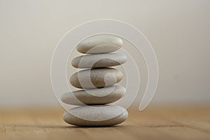 Stone cairn on wooden background, five stones tower, simple poise stones, simplicity harmony and balance, rock zen
