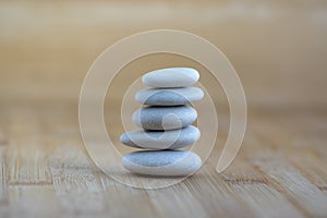 Stone cairn on wooden background, five stones tower, simple poise stones, simplicity harmony and balance, rock zen