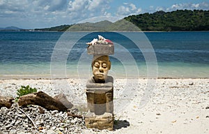 Stone carving man sitting on the beach on high travelling season of Indonesia.