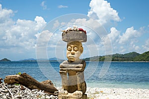 Stone carving man sitting on the beach on high travelling season of Indonesia.