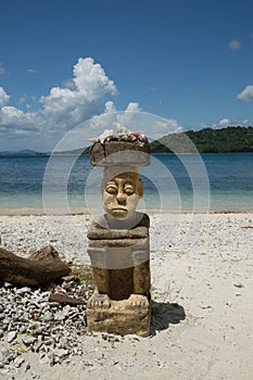 Stone carving man sitting on the beach on high travelling season of Indonesia.