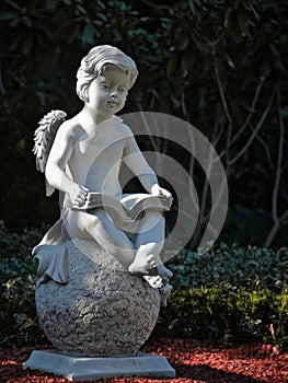 Stone child angel reading a book on a sphere