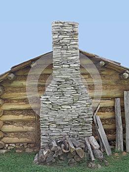 Stone chimney on wall of log cabin.