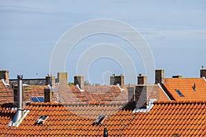 Stone chimneys on the roofs with orange roof tiles