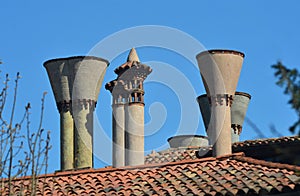 Stone chimneys on a terracotta roof rise against a blue sky